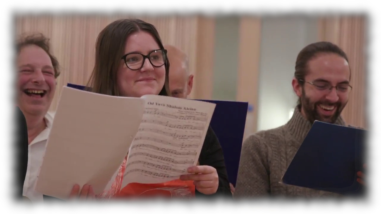 Choir members during a rehearsal, holding music folders and having a good time.